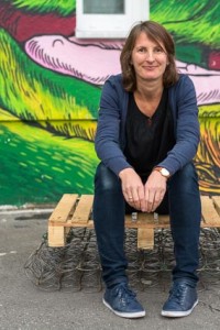 Stephanie Haury sitzt vor einer Graffiti-besprühten Wand